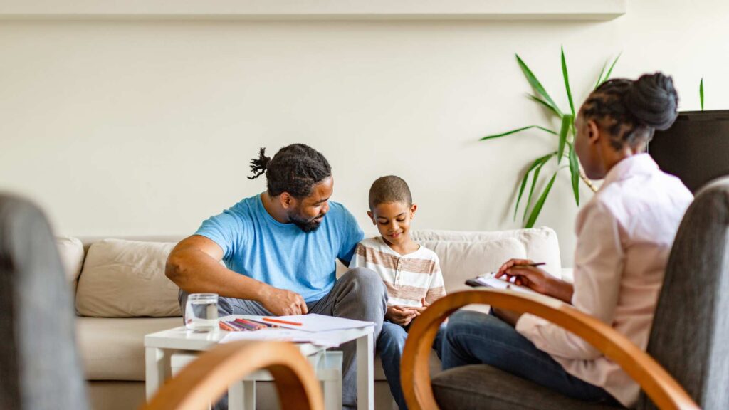 Autism Co-Occurring Conditions: What A Diagnosis Doesn’t Always Reveal A parent and child sitting together while an aba therapy professional takes notes nearby, as support to autism co-occurring conditions