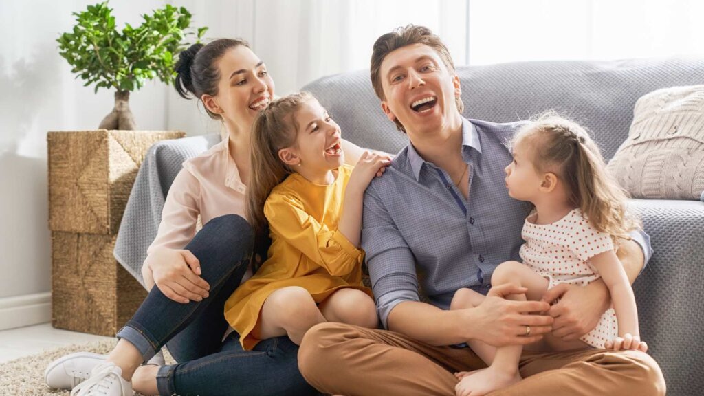 Family sitting on a living-room floor, smiling and engaged—showing trust, warmth, and collaboration in aba