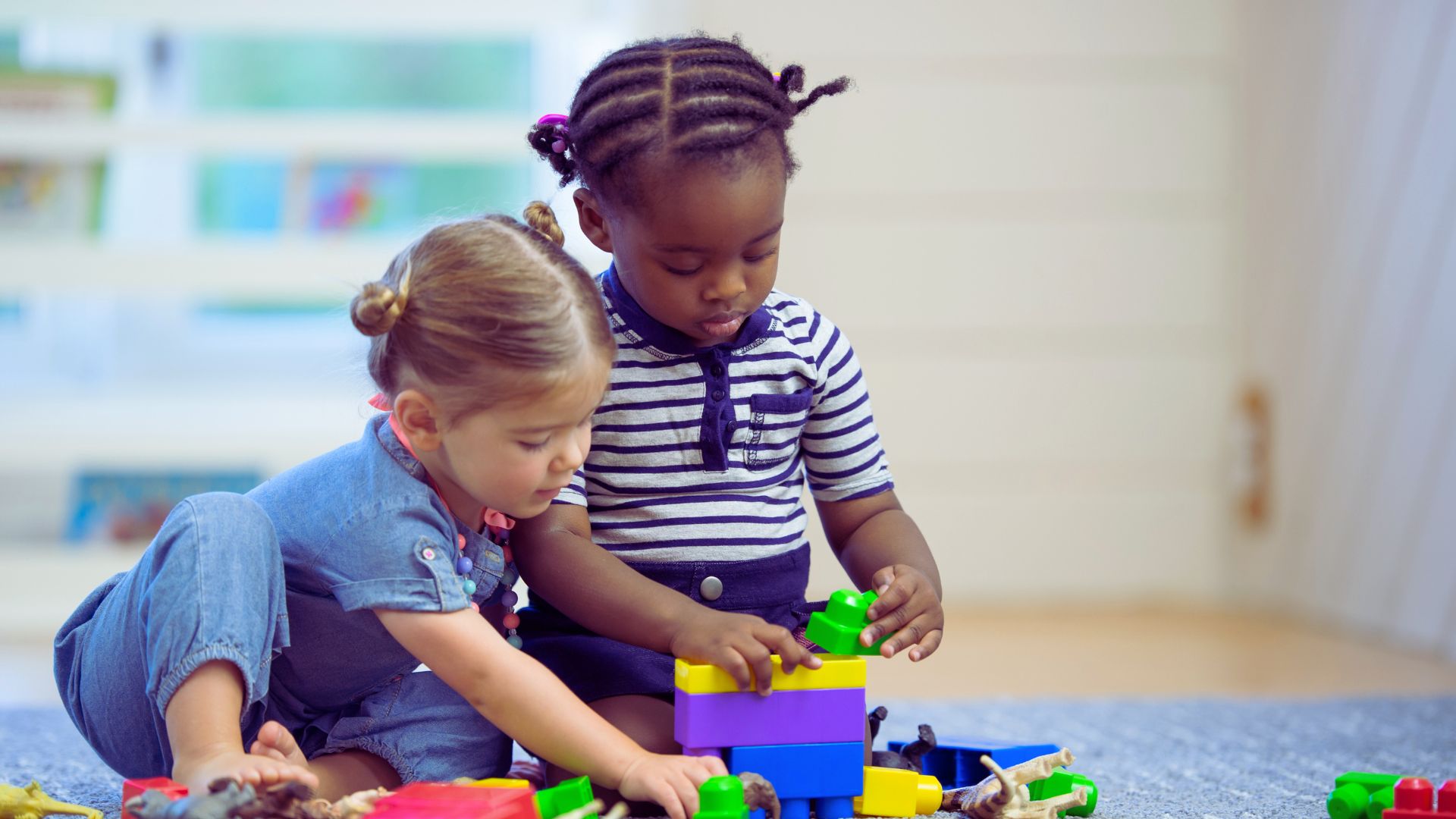 Two young children playing with colorful blocks, illustrating how early should ABA therapy start and the role of early intervention for autism in building play and social skills.