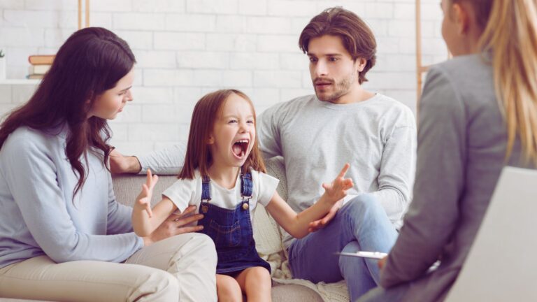 Parents discuss autism concerns with a specialist while their child expresses big emotions, showing how to talk to a pediatrician about autism.