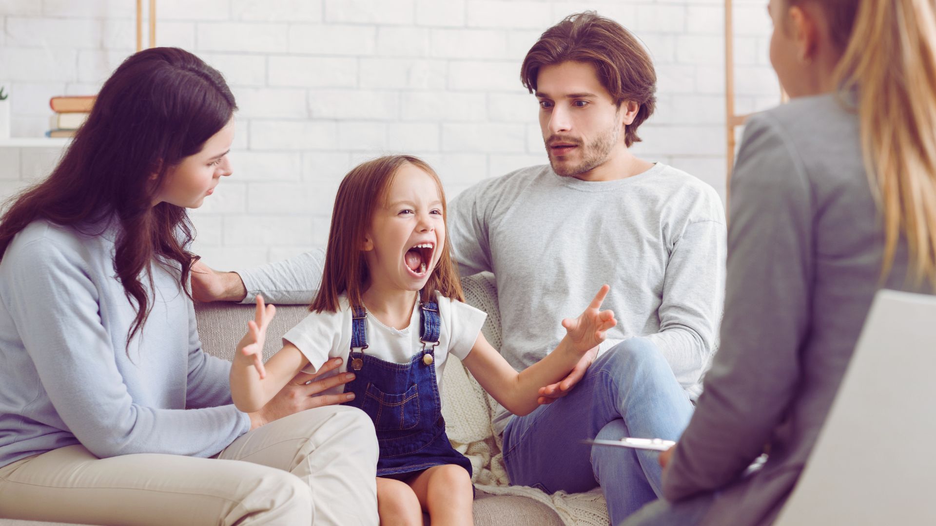 Parents discuss autism concerns with a specialist while their child expresses big emotions, showing how to talk to a pediatrician about autism.