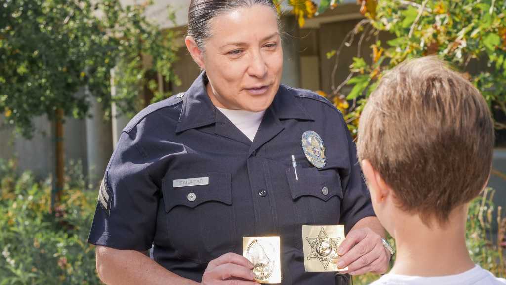 Female police officer interacting with a young boy, representing the compassionate approach of daay for autistic youth in the justice system.