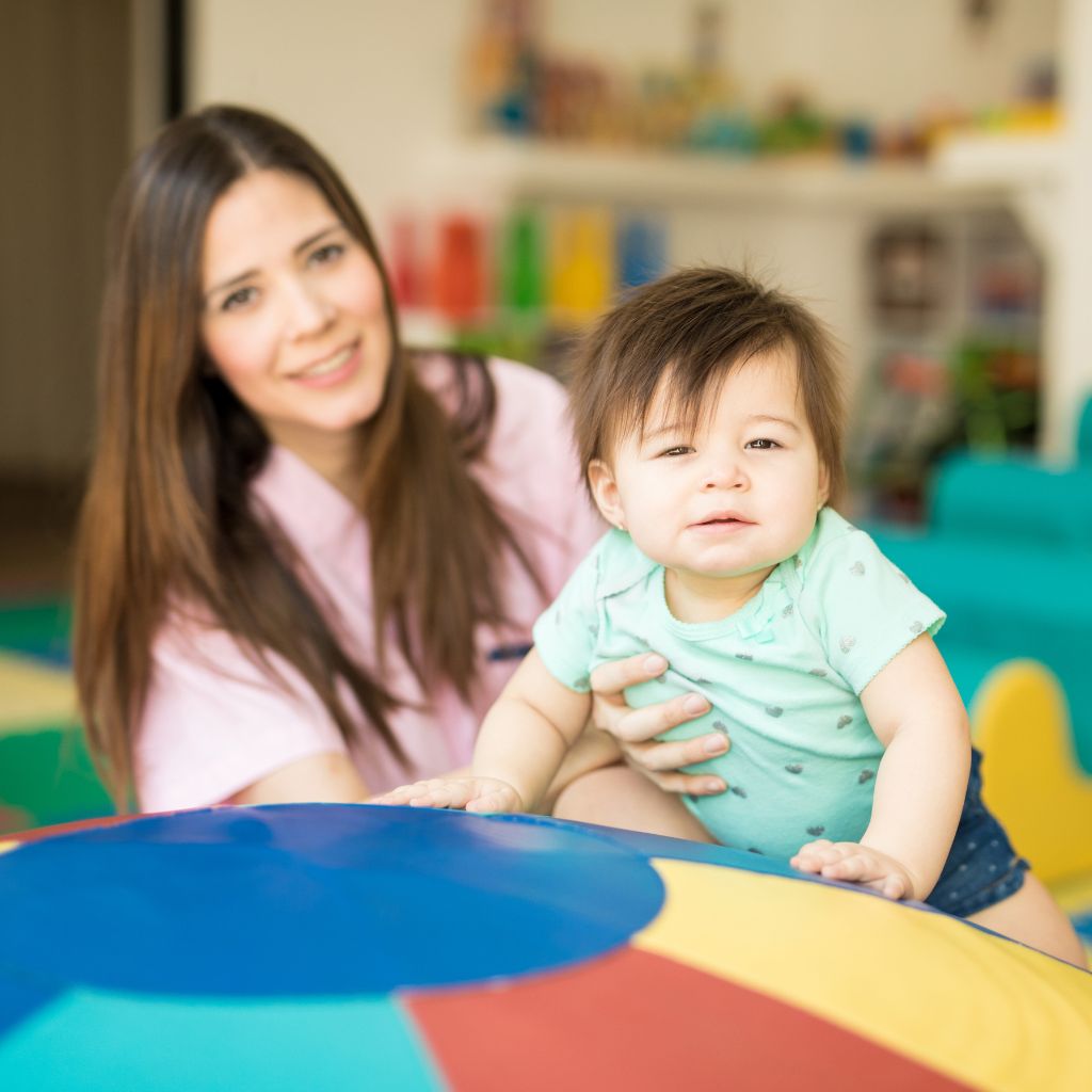 Smiling therapist supporting a young child during play—representing early intervention and the benefits of aba therapy for children with autism.