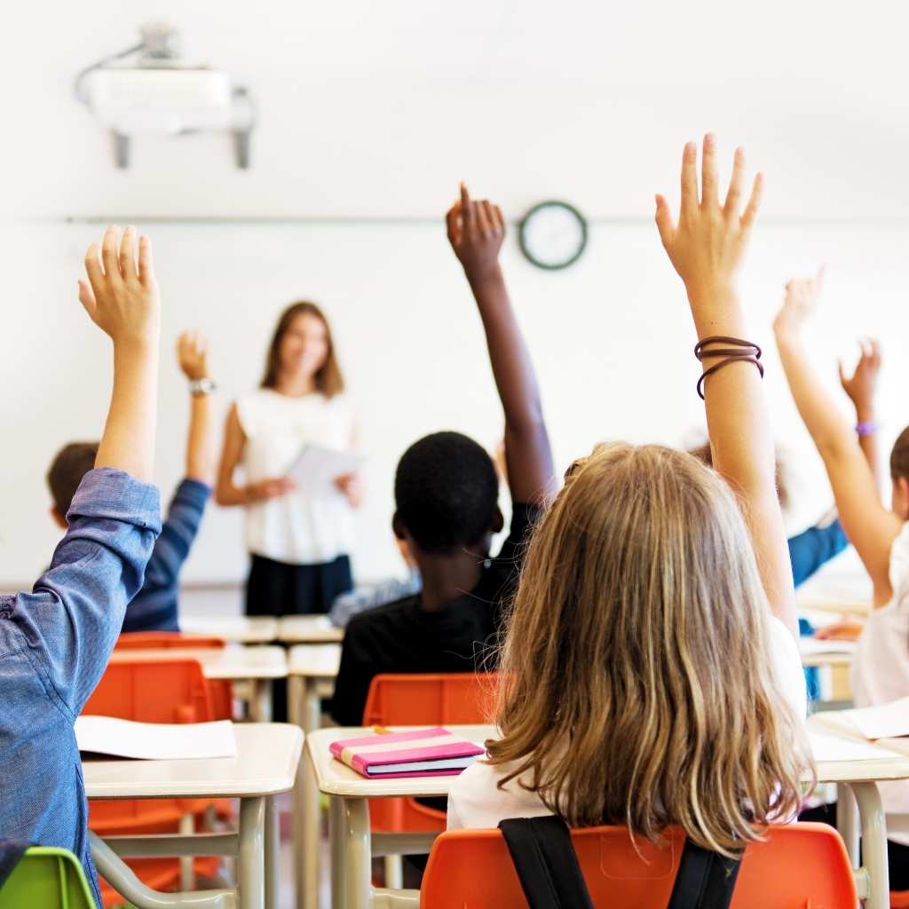 Students participating in a classroom by raising their hands during a lesson