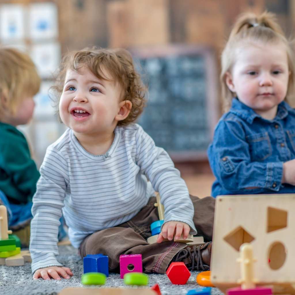 Toddler smiling while playing with toys, an small moment that shows aba therapy progress