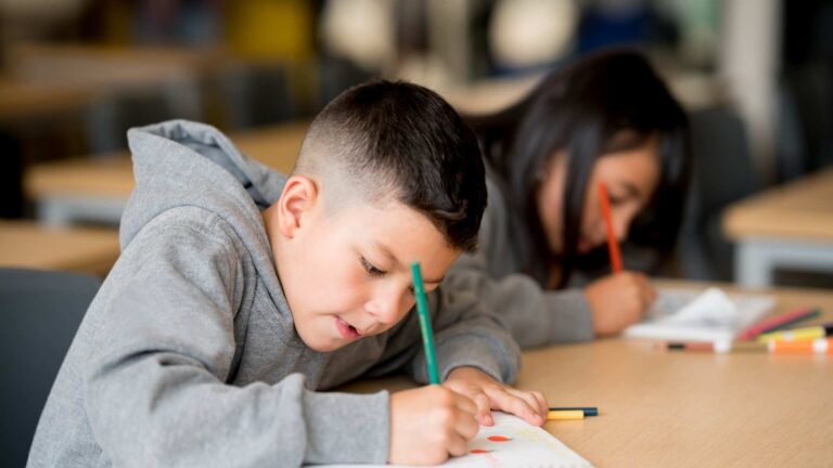 Student completing a classroom assignment on desk
